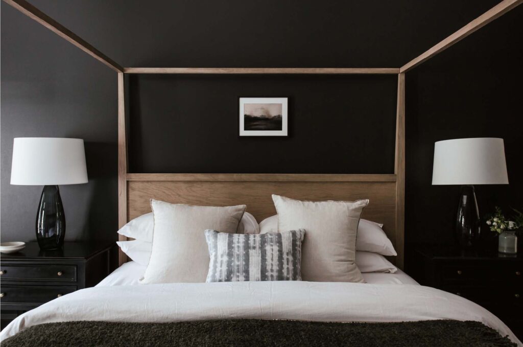 Primary Suite bed. Wood grain minimalist canopy be on black walls.