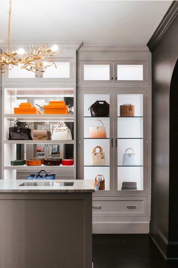 Her closet with black walls and white lighted glass front handbag display cases