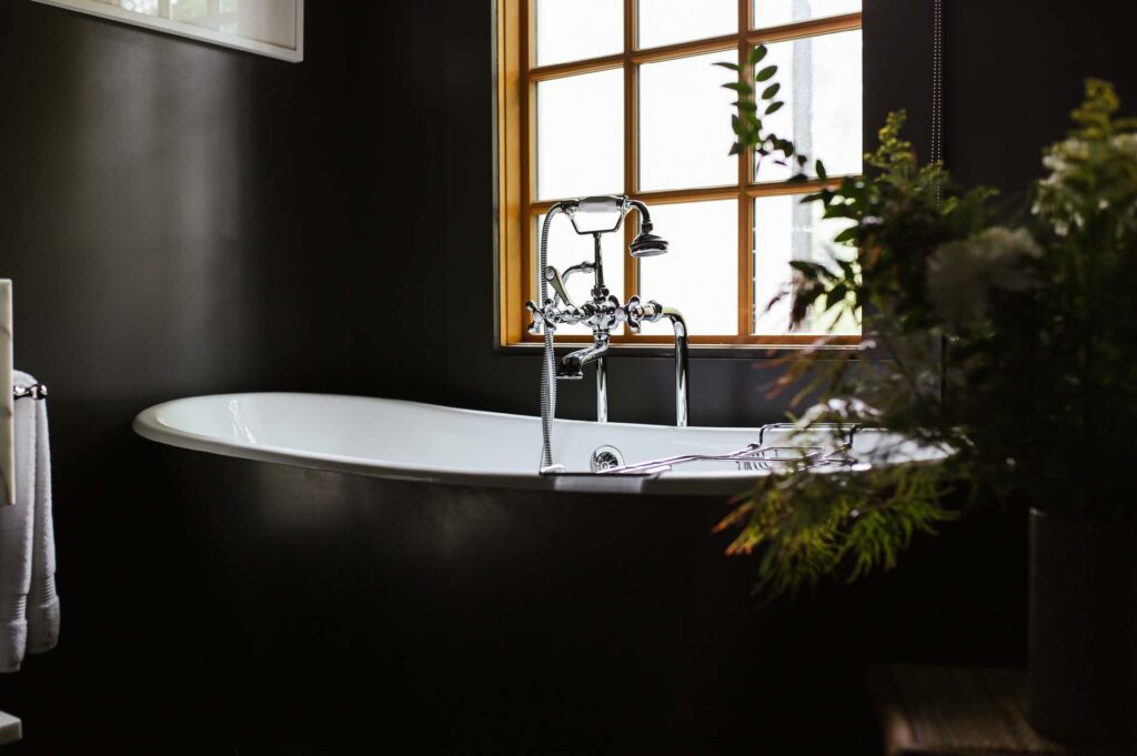 Her bathroom with black freestanding tub, porcelain tub interior and chrome fixtures.