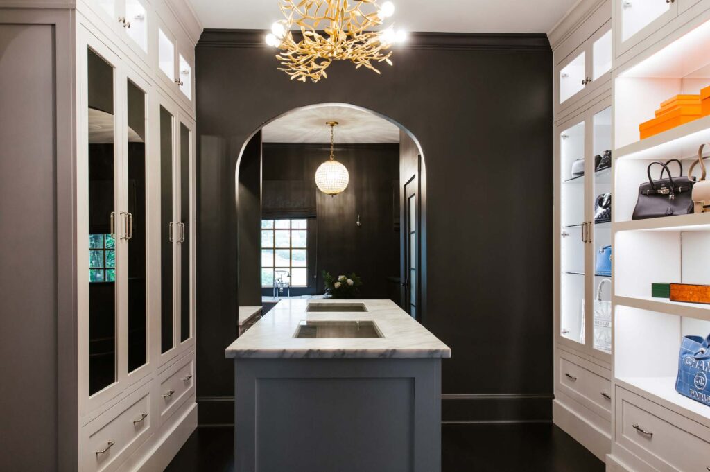 Her closet with black walls and white lighted glass front handbag display cases