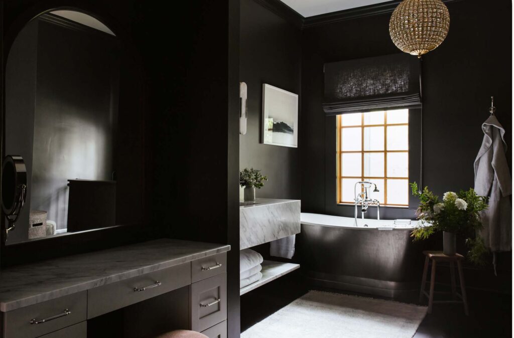 Her bathroom with black walls and black and white tub, marble counters