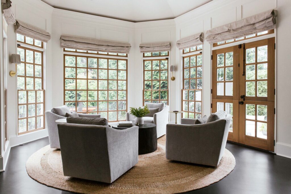 lounge area with wooden coffee table, grey lounge chairs, bay windows