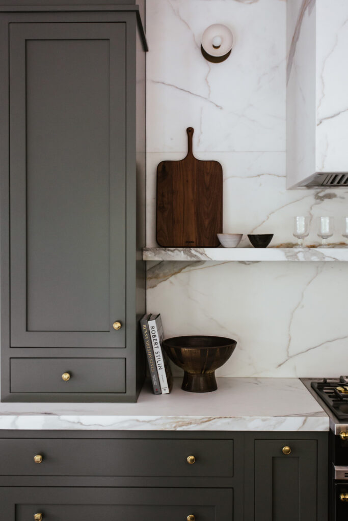 grey cabinets, wooden cutting board and metal bowls on marble shelves