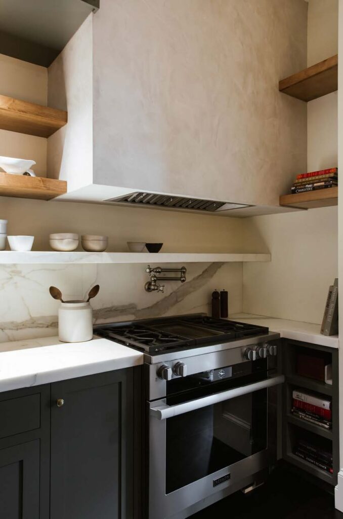 A Miele range is tucked into the corner with a plaster hood above.