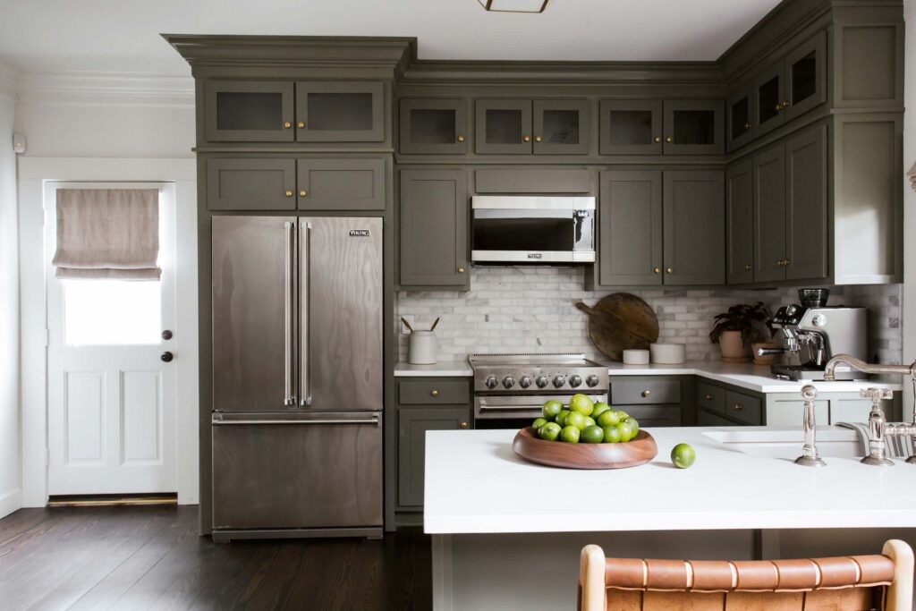 Guest kitchen with olive cabinets, pure white counters and gray marble backsplash.