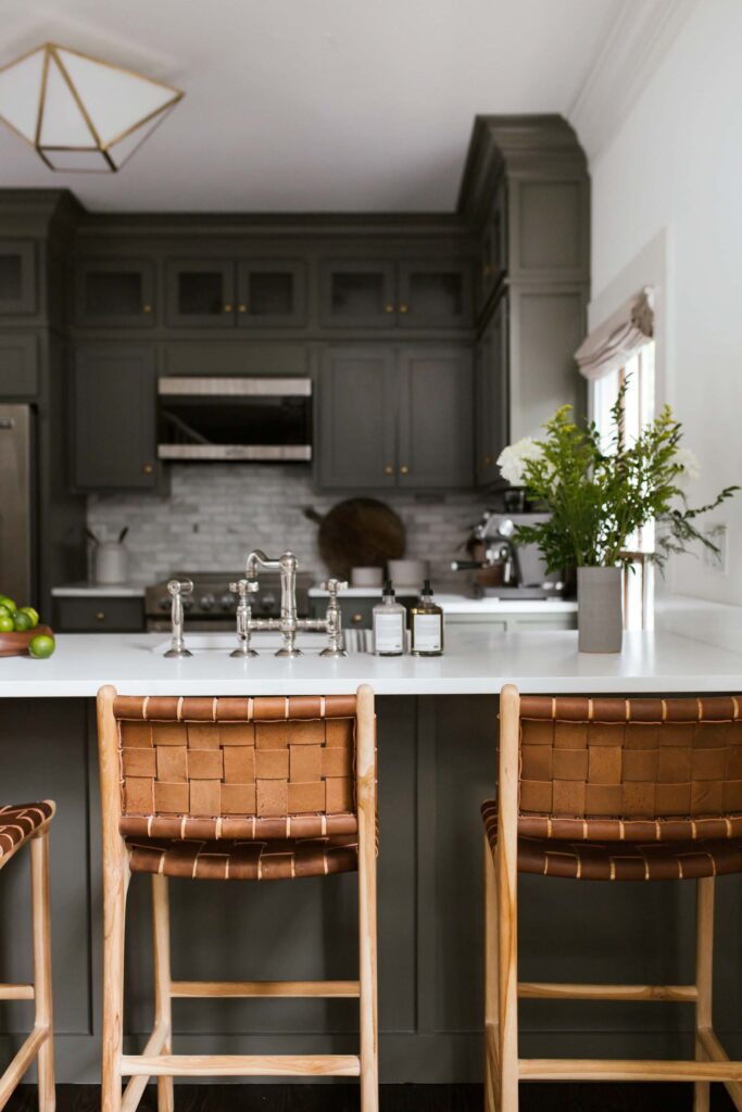 Guest kitchen white quartzite pennisula with chrome faucets and natural woven leather bar stools.